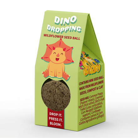 A green paper stand-up pouch package for a 'Dino Dropping' wildflower seed ball, featuring a cartoon orange lion illustration and a clear window showing the dark brown seed ball inside.