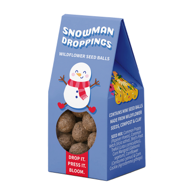 A blue stand-up packaging box for 'Snowman Droppings' wildflower seed balls, featuring a cartoon snowman, a clear window showing the brown seed balls inside, and a red label that reads 'DROP IT. PRESS IT.