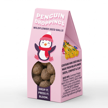 Pink retail packaging for Penguin Droppings Wildflower Seed Balls, featuring a penguin illustration and a clear window showing the round seed balls inside.