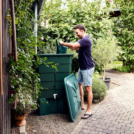 Man interacting with green recycling bins outdoors